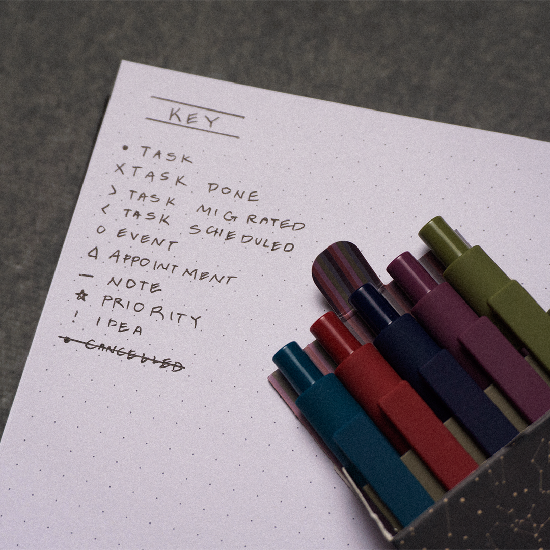 Bullet journal key page showing task symbols with colorful GuyGottaChange gel pens arranged alongside